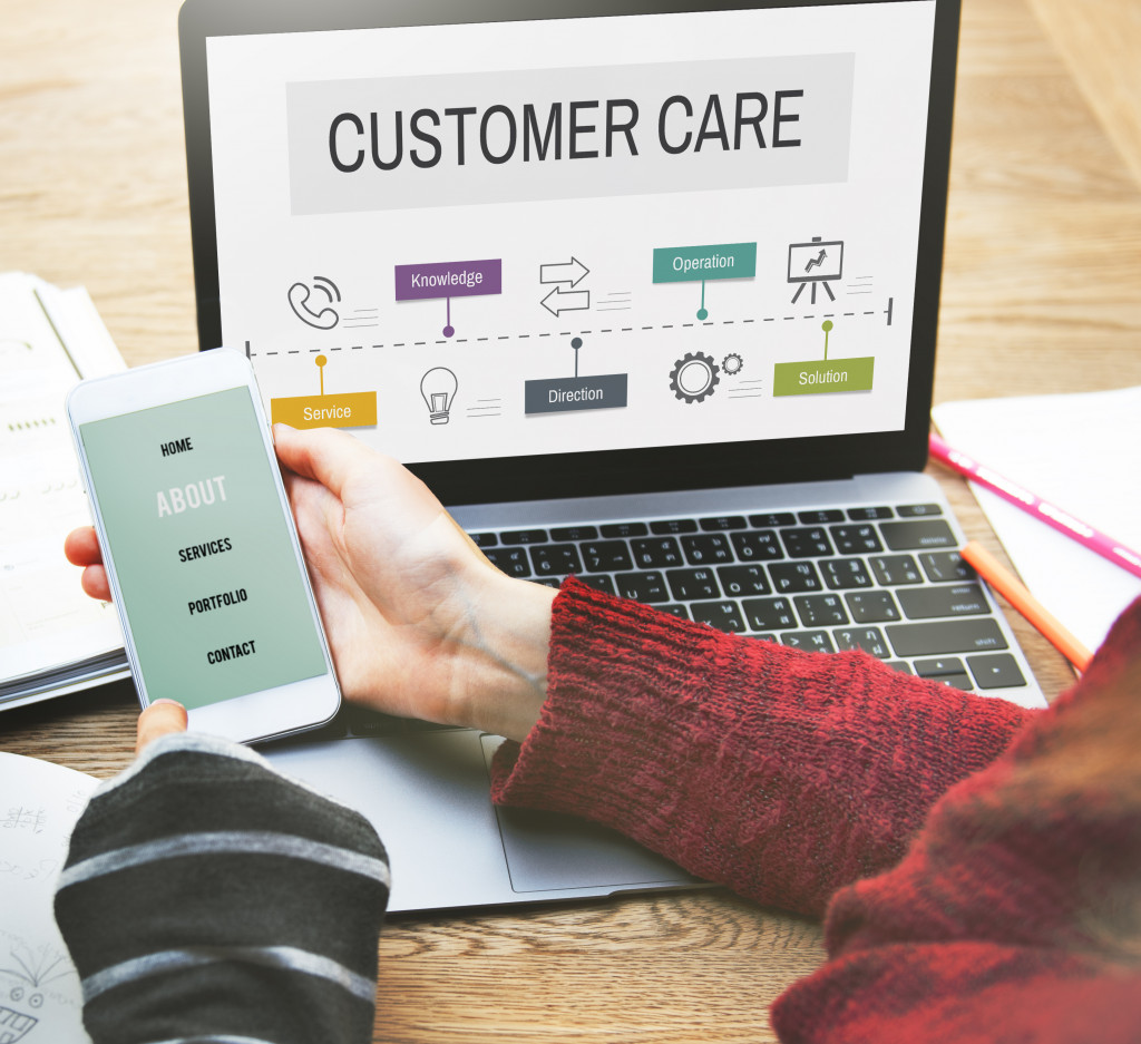 laptop and customer care in the screen, woman holding a smartphone