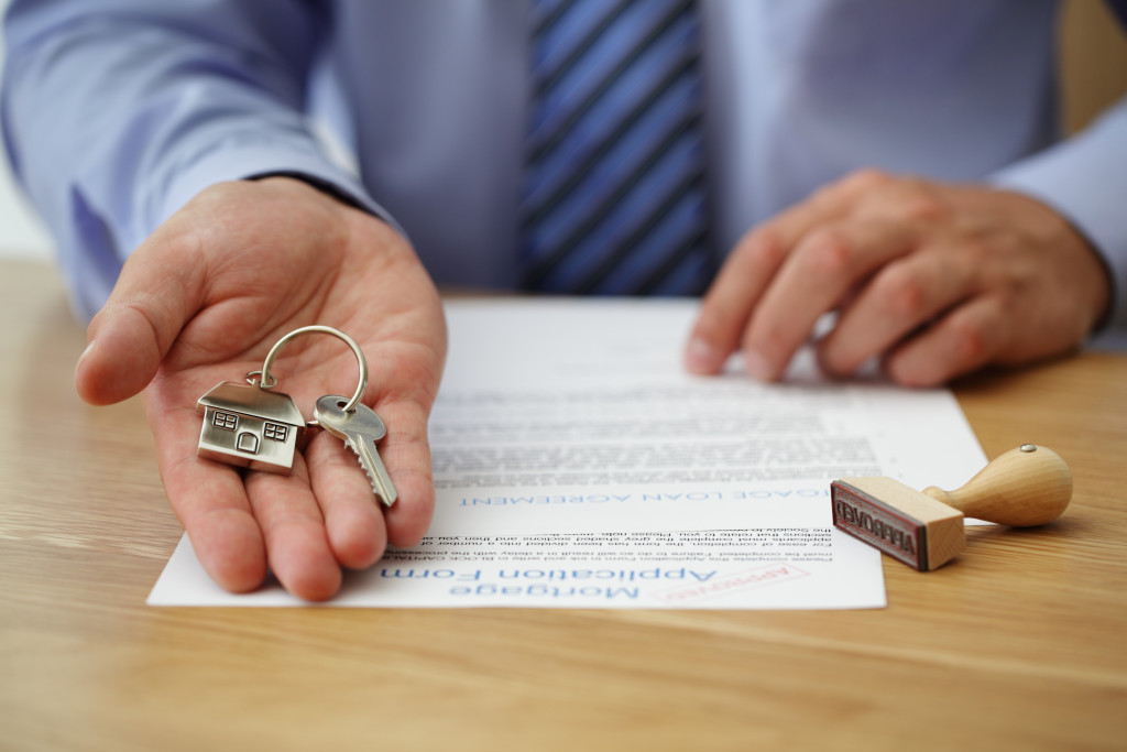 man handling the key with a house keychain and a document in the table