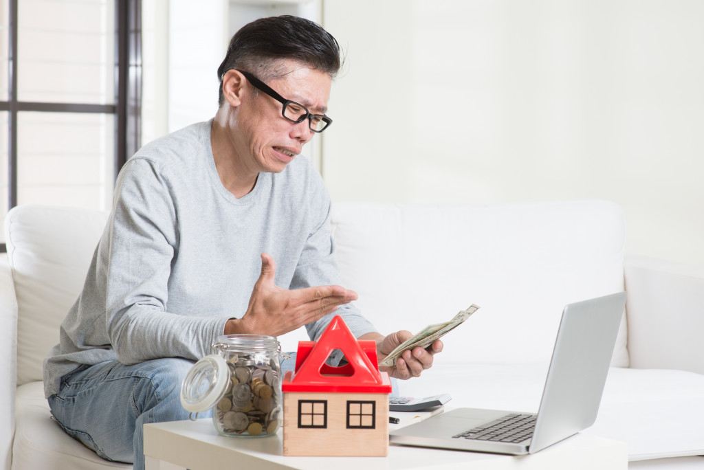 an old man looking at money in front of a laptop