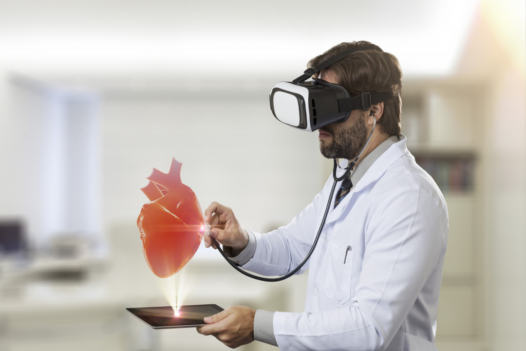 Male doctor in his office,using a Virtual Reality Glasses, looking at a virtual heart.