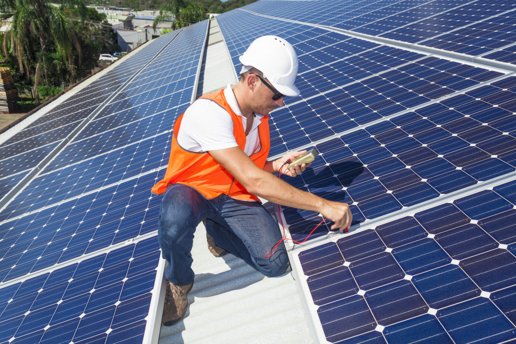 Young technician checking solar panels on factory roof