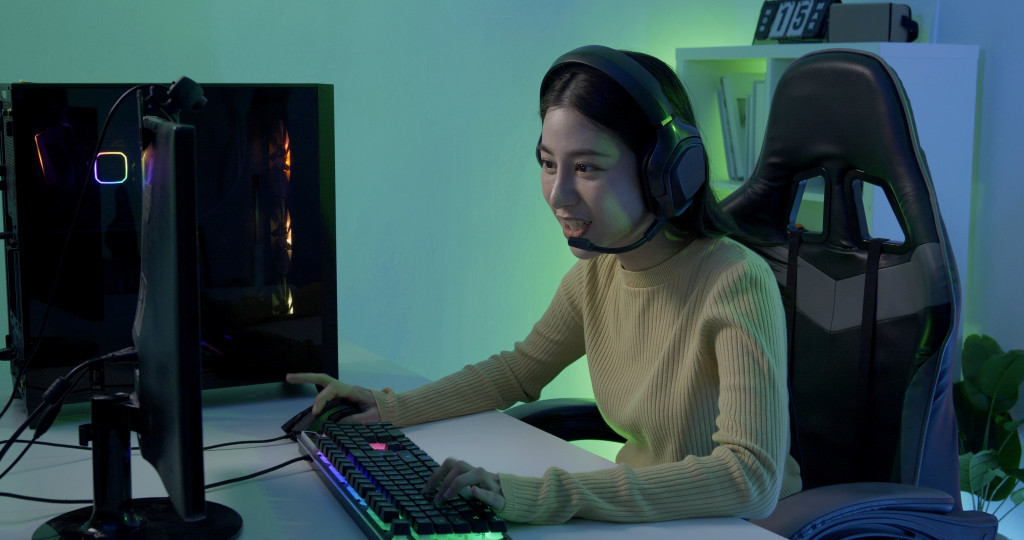 a woman sitting on a comfortable chair and playing games on a PC 