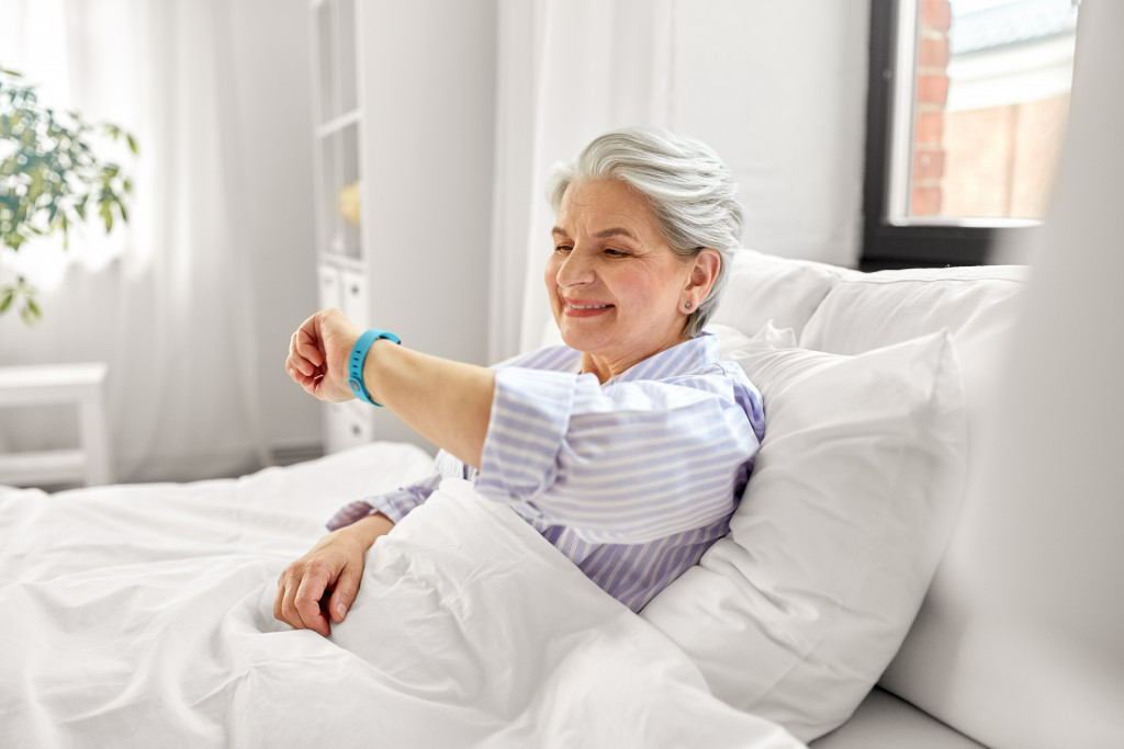 senir in bed looking at her wearable device for health