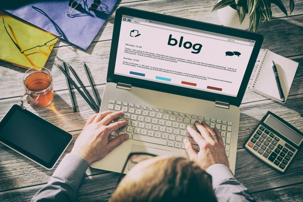 A person writing a blog on a cluttered desk