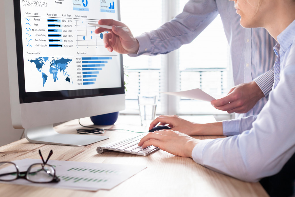 Two people using a computer to analyse business data