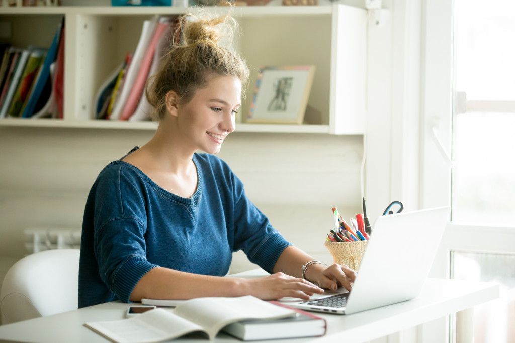 student with bookd and notebook in an online class