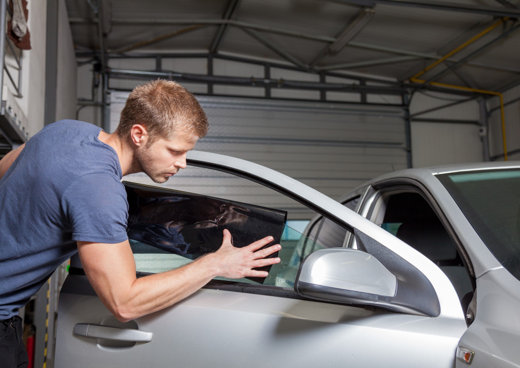 man applying car tint for sun protection