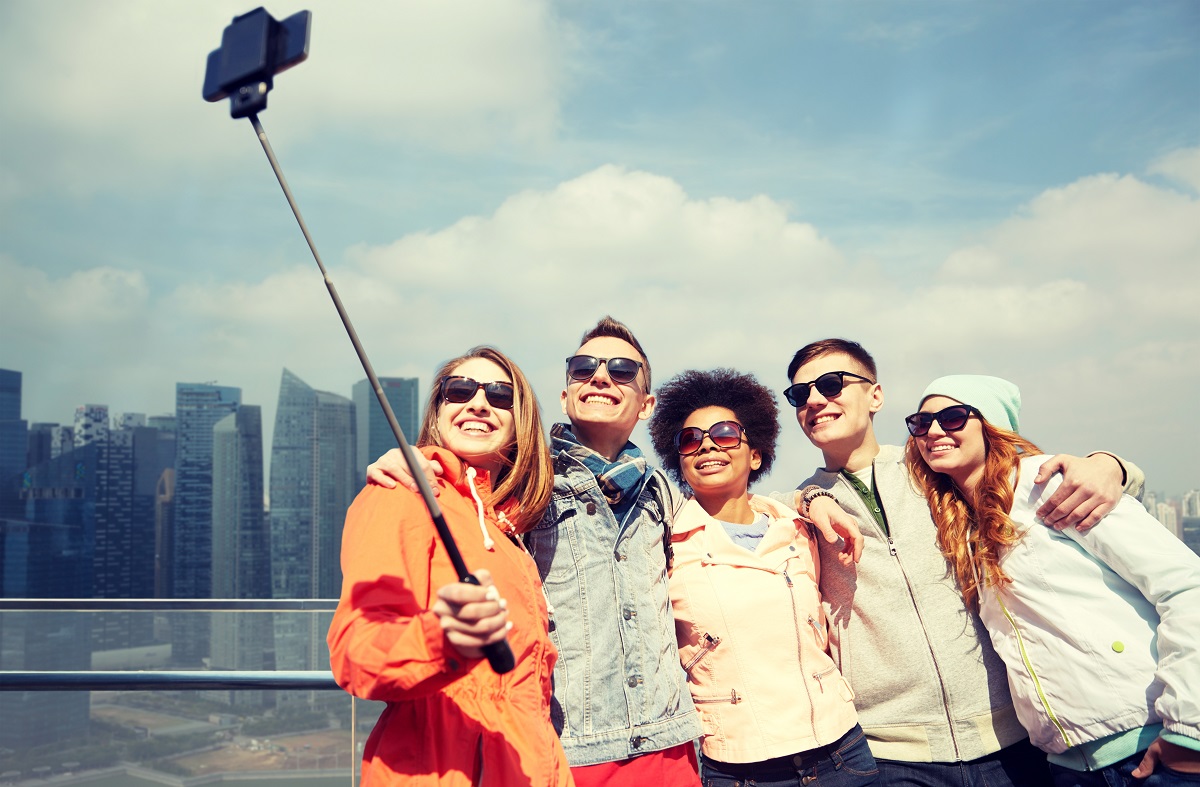 group of friends taking photos using selfie stick