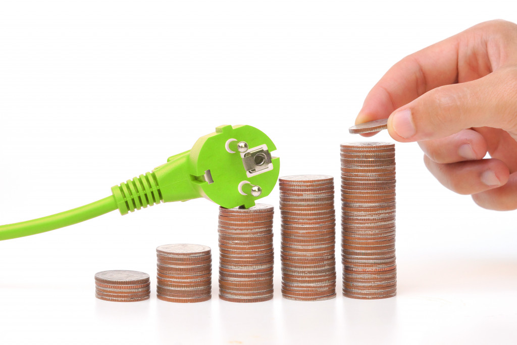 green plug on top of coins concept of energy efficiency
