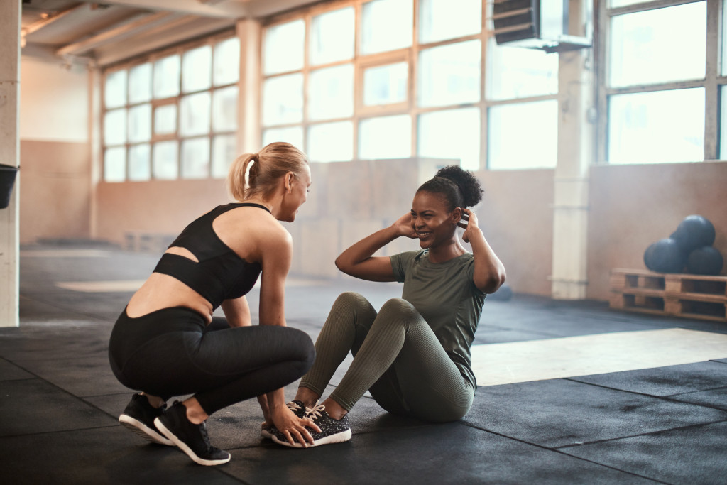 fit american coach helping african american woman with situps