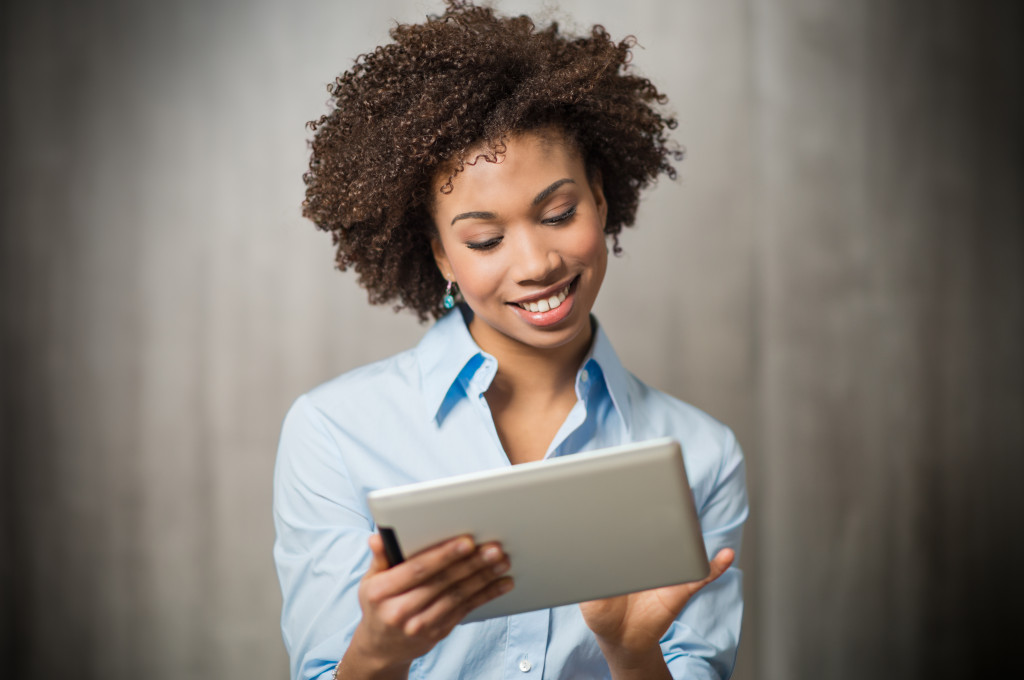 woman using a tablet while smiling