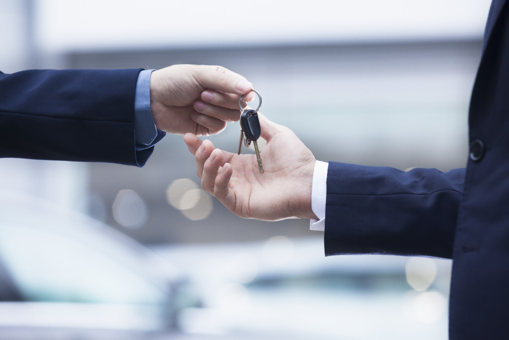 car salesman handing keys to car owner